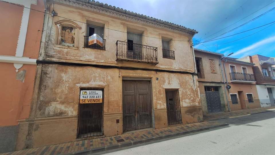Fachada de una casa de pueblo en venta en Chella con el cartel de Cano Boluda